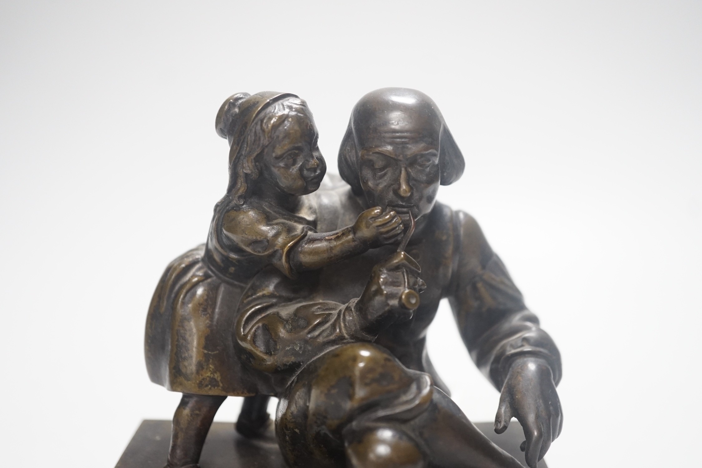 A 19th century bronze group of a gentleman smoking a pipe and a girl, on slate base 18.5cm wide